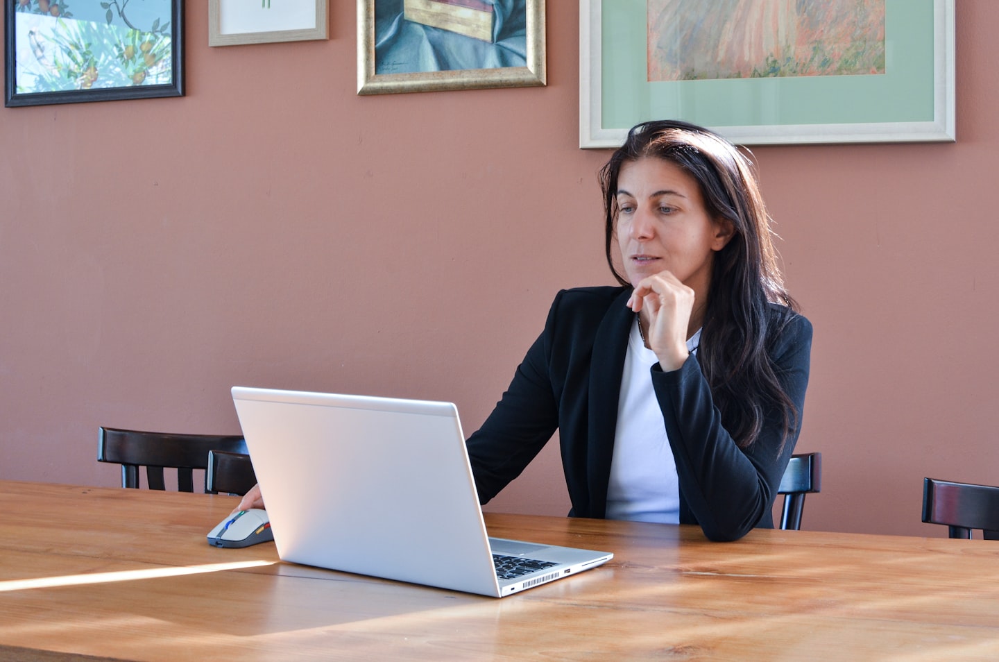 Woman in a black blazer working on a laptop