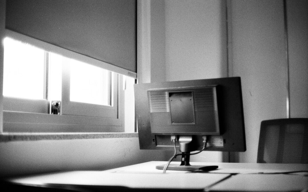 A black and white photo of a desk with a computer