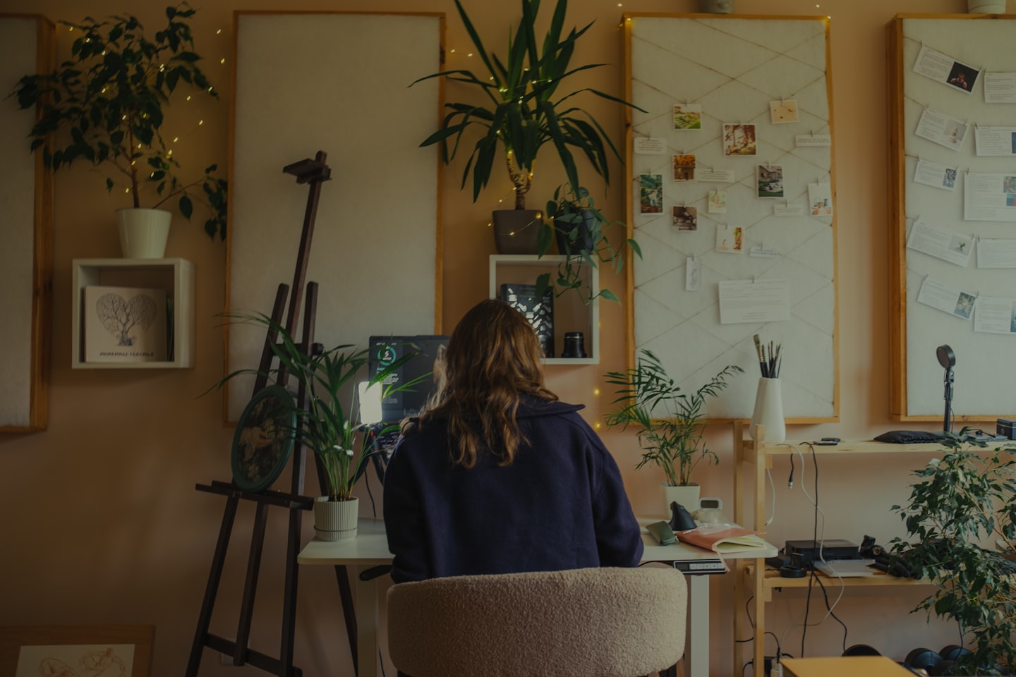 Woman working at a desk in a plant-filled studio