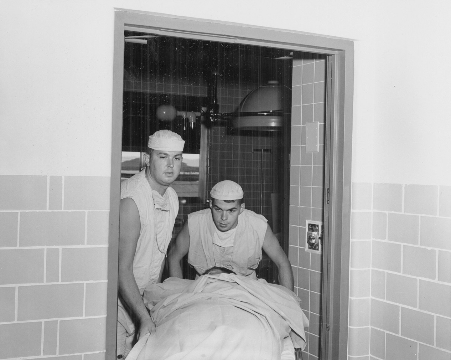 Two medical professionals transport a patient on a gurney
